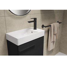 Wastafel met zwarte onderkast, kraan, handdoekhouder en handdoek in een badkamer.