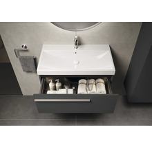 Moderne badkamer met wastafelonderkast, open lade en handdoeken.