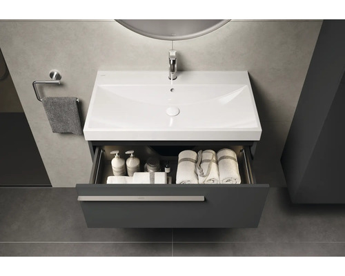 Moderne badkamer met wastafelonderkast, open lade en handdoeken.