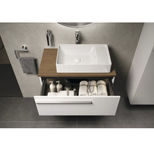 Moderne badkamer met witte waskom op houten blad en open lade-element gevuld met handdoeken en verzorgingsproducten.