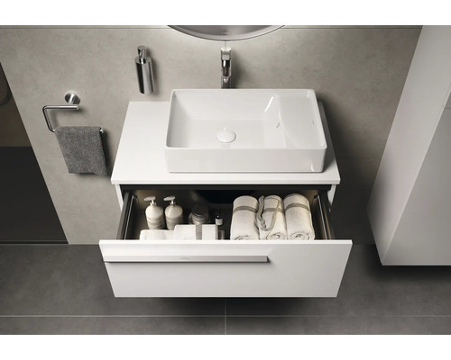 Moderne badkamer met wastafel, wasbak en open lade met handdoeken en badkamerbenodigdheden.