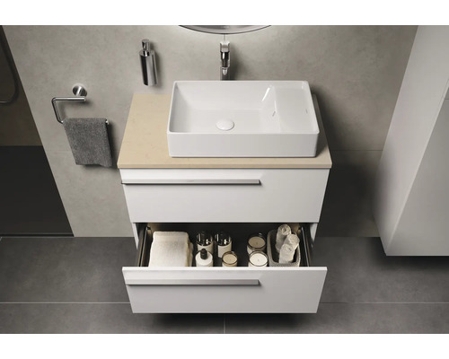 Moderne badkamer met witte wastafelonderkast en open lade met badkamerbenodigdheden.