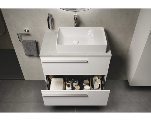 Moderne badkamer met wit badkamermeubel, waskom en open lade met badkameraccessoires.