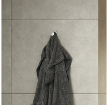 Grijze badjas hangt aan een wandhaak in de badkamer.