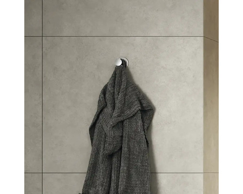 Grijze badjas hangt aan een wandhaak in de badkamer.