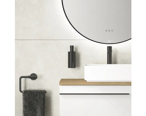 Badkamer met ronde spiegel, wastafel, kraan, zeepdispenser en handdoekhouder