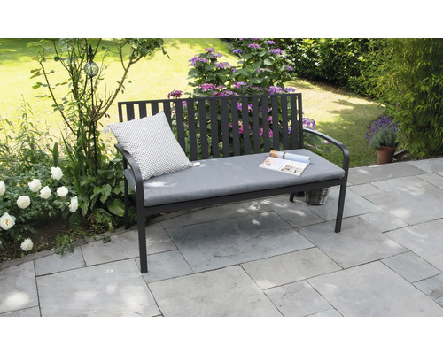 Tuinbank met kussen en tijdschrift in de tuin