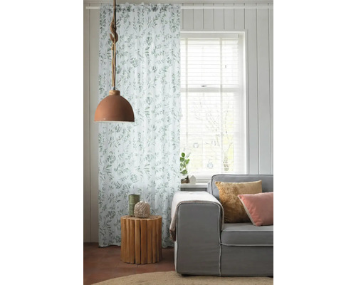 Woonkamer met gordijn met bladmotief, lamp en bank