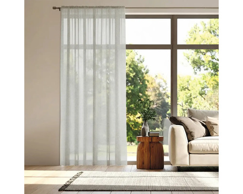 Woonkamer met gordijn voor het raam, bank en vloerkleed