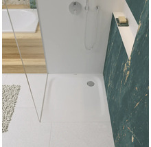 Badkamer met douche, douchebak, kraan en betegelde wand