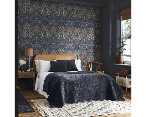 Slaapkamer met patroonbehang, bed met hoofdeinde van rotan en decoratief tapijt