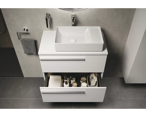 Moderne badkamer met wastafelonderkast, opzetwastafel en open lade voor het opbergen van badkamerartikelen.