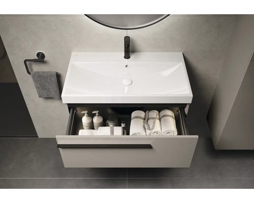 Wastafel met open lade, handdoeken en badkamerbenodigdheden in een moderne badkamer