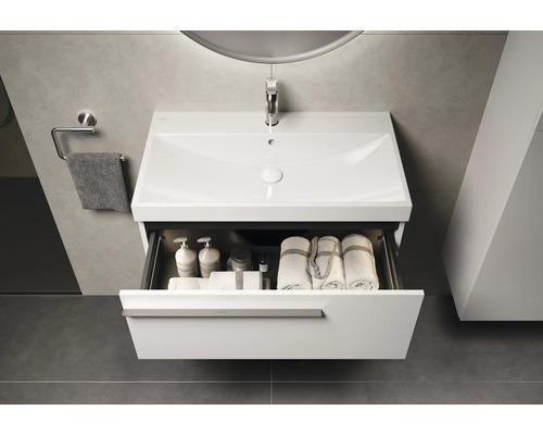 Wastafelmeubel met open lade, handdoeken en badkamerbenodigdheden in de badkamer.