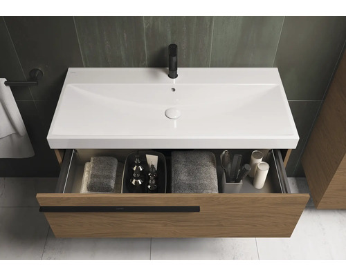 Wastafelonderkast met open lade, voorzien van handdoeken en badkamerbenodigdheden