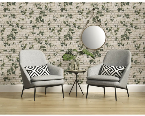 Woonkamer met twee grijze fauteuils, een ronde spiegel en behang met baksteen- en klimopmotief