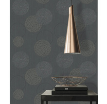 Close-up van een muur met een bloemmotief behang, een lamp en een tafel