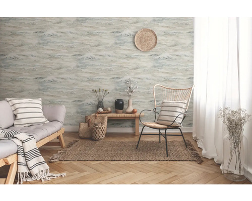 Woonkamer met patroonbehang, bank en fauteuil op een vloerkleed