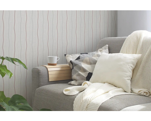 Woonkamer met patroonbehang, bank, kussens en bijzettafel