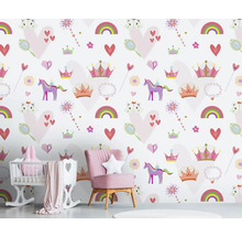 Kinderkamer met behang met eenhoorn-, regenboog- en hartmotieven, met roze fauteuil en babybed