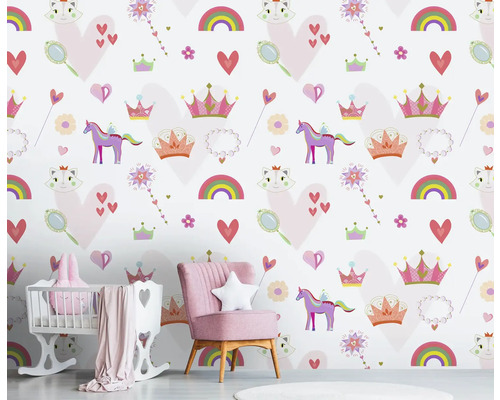 Kinderkamer met behang met eenhoorn-, regenboog- en hartmotieven, met roze fauteuil en babybed