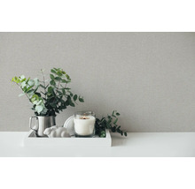 Decoratieve stillevenopstelling met gestructureerde achtergrond, bestaande uit kaars, ornament en plant.