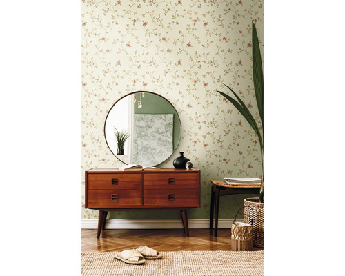 Woonkamer met bloemenbehang, ladekast, spiegel en decoraties.