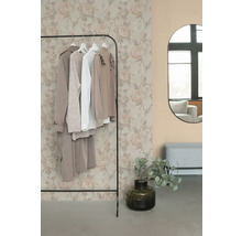 Kledingrek met kleding, spiegel en decoratie in een kamer.