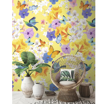 Decoratief interieur met geel behang, versierd met bloemen, vlinders en vogels, aangevuld met een rotan stoel en kamerplanten