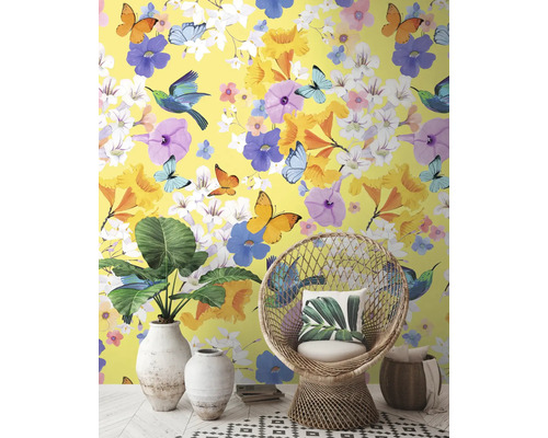 Decoratief interieur met geel behang, versierd met bloemen, vlinders en vogels, aangevuld met een rotan stoel en kamerplanten