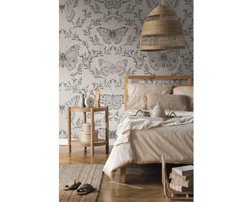 Slaapkamer met bed, nachtkastje, lamp en behang met vlinderpatroon