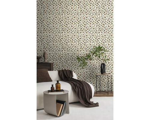 Woonkamer met behang in luipaardmotief, bank, bijzettafels en decoraties.