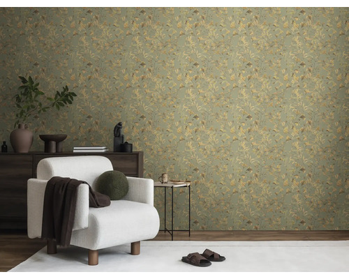 Woonkamer met een groen behang met plantenmotief, een witte fauteuil en een donker dressoir