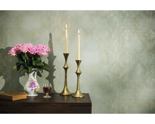 Decoratieve opstelling met rozen, kaarsen en antieke elementen op een tafel voor een wand met patroon