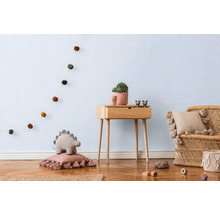 Lichte kinderkamer met houten vloer, houten tafel, rotan stoel en decoratieve elementen zoals een slinger, kussens en een plant.