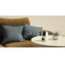 Imou bewakingscamera op een tafel naast een kamerplant en een bank