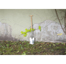 Spade met houten handvat tegen een muur