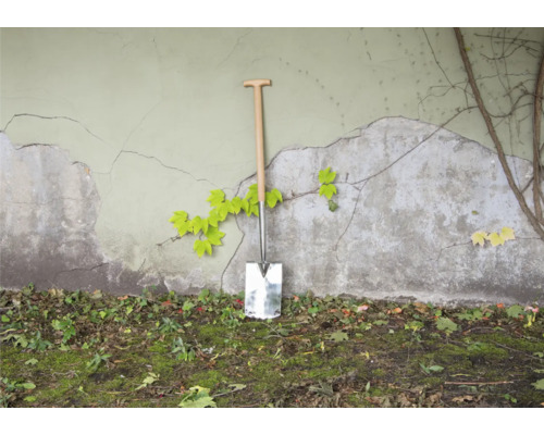 Spade met houten handvat tegen een muur