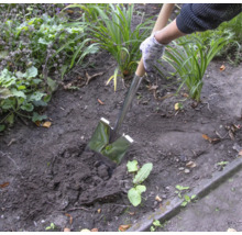 Persoon gebruikt een spade om in de tuin te graven.