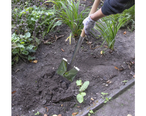 Persoon gebruikt een spade om in de tuin te graven.
