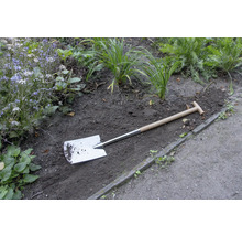 Spade met houten handvat in de tuinperk