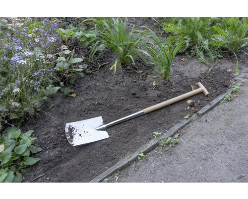 Spade met houten handvat in de tuinperk