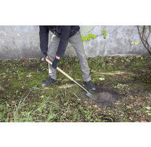 Een persoon graaft een gat in de tuin met een spade.