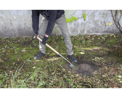Een persoon graaft een gat in de tuin met een spade.