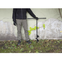 Persoon met grondboor in de tuin