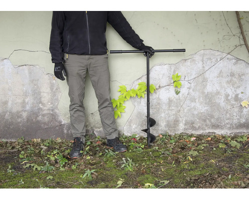 Persoon met grondboor in de tuin