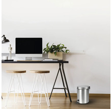 Scene met een bureau, krukken en een metalen afvalemmer met voetpedaal