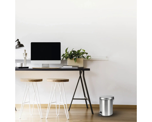 Scene met een bureau, krukken en een metalen afvalemmer met voetpedaal