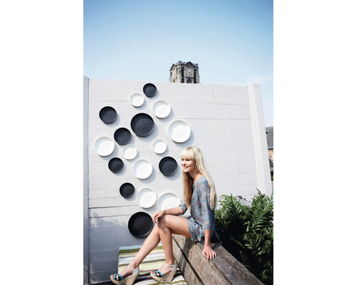 Decoratieve muur met siersierborden buitenshuis met vrouw op een bank