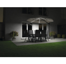 Tuin met eettafel, stoelen en verlichte parasol in de avond